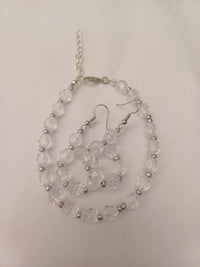 A necklace and earrings set made of transparent faceted beads with silver spacers. The necklace has a silver chain and clasp.