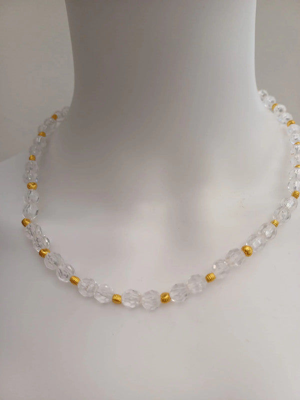 A clear beaded necklace with faceted beads interspersed with small gold spacers, displayed on a white mannequin bust.