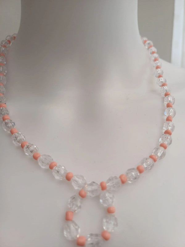 A clear and pink beaded necklace displayed on a white mannequin bust. The necklace features alternating transparent and pink beads.