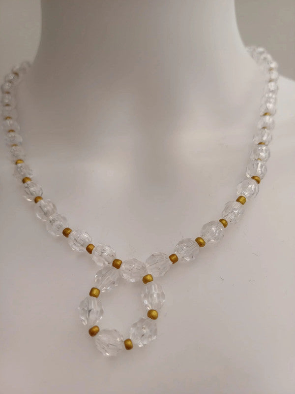 A clear crystal beaded necklace with small gold spacer beads, featuring a looped pendant design, displayed on a white mannequin bust.
