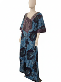 A mannequin displays the Elegant Blue & Purple Ankara Kaftan Dress, featuring a long, loose fit with bold dark floral patterns and detailed pink embroidery on the chest and sleeves, set against a plain white background.