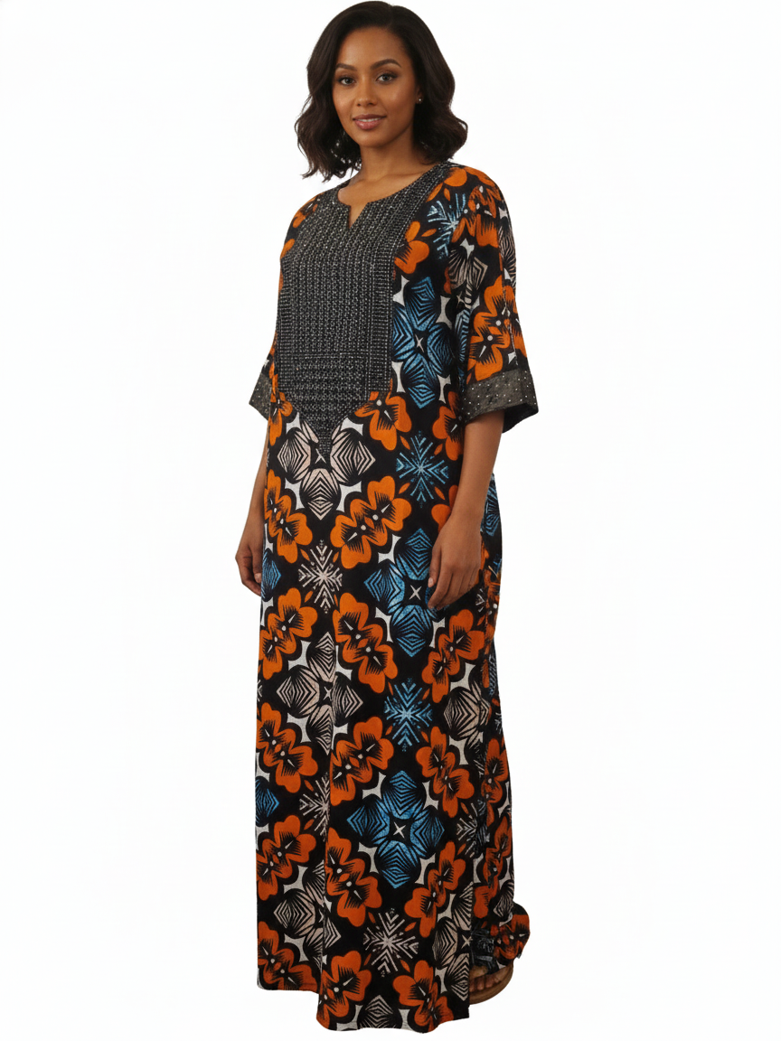 A woman with shoulder-length dark hair and a neutral expression wears the African Print Maxi Dress – Vibrant Floral Pattern, showcasing bold orange, blue, and black geometric and floral designs plus a black-and-white patterned chest panel.