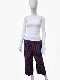 A mannequin wearing a white tank top and colorful wide-leg pants with a swirling pattern in purple, blue, and orange.