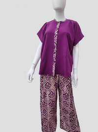 Mannequin in a purple short-sleeve top with patterned trim and matching wide-leg pants with geometric designs on a plain background.