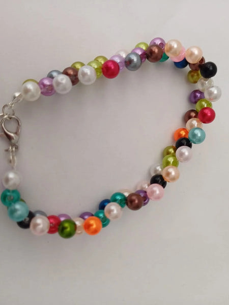 A bracelet made of small, multicolored beads, including pink, green, blue, and white, with a silver chain and clasp, on a white background.
