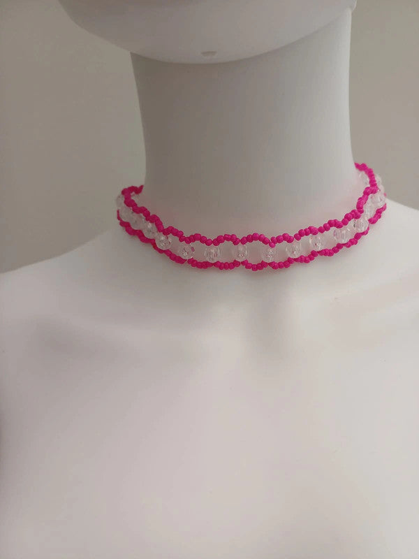 A mannequin displays a pink and white beaded choker with a scalloped design around its neck. The background is neutral.