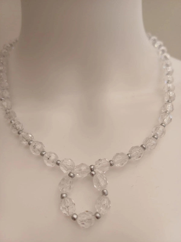 A clear bead necklace with a circular pendant design on a white mannequin bust. The necklace features faceted beads with small silver spacer beads.