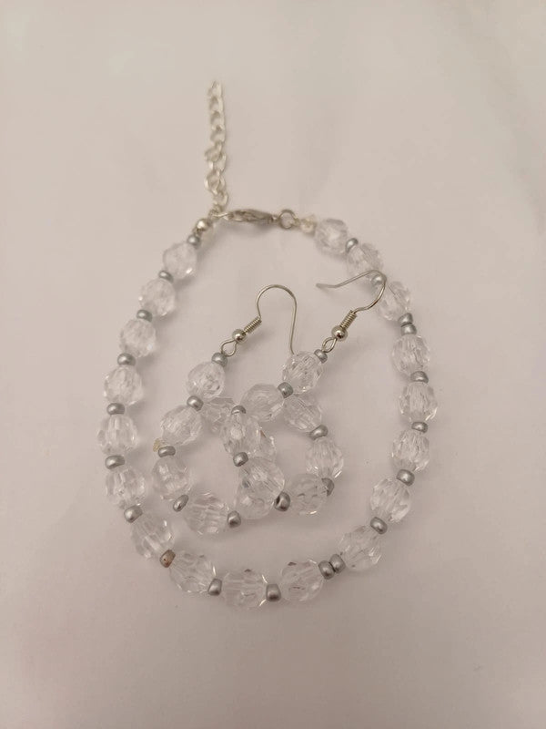 A necklace and earrings set made of transparent faceted beads with silver spacers. The necklace has a silver chain and clasp.