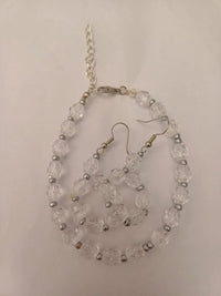 Clear beaded necklace and earrings set with silver accents, displayed on a white background. The necklace features a chain clasp.
