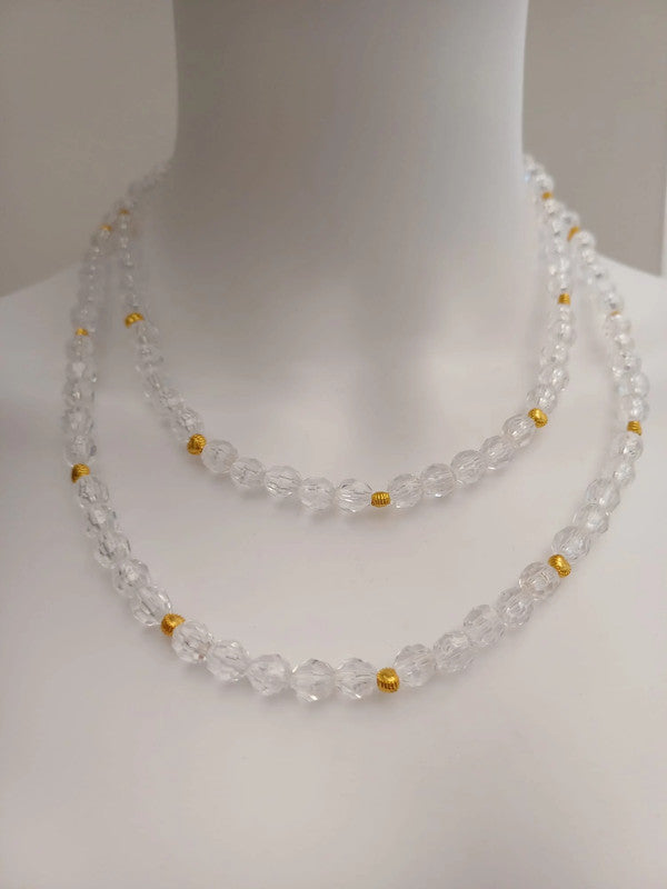 A mannequin wearing a double-strand necklace made of clear, round beads with small gold spacers, set against a plain background.