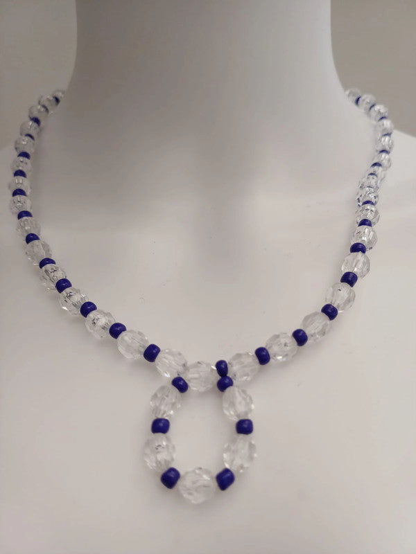 Necklace with clear faceted beads and small blue beads, arranged in a pattern, displayed on a white mannequin bust.