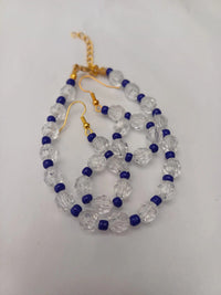 Gold hook earrings with clear faceted beads and small blue round beads, arranged in a loop pattern on a white background.