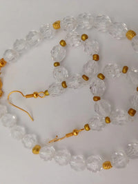 A necklace and earring set with clear, faceted beads and gold accents. The necklace has a gold chain and clasp, with matching earrings.