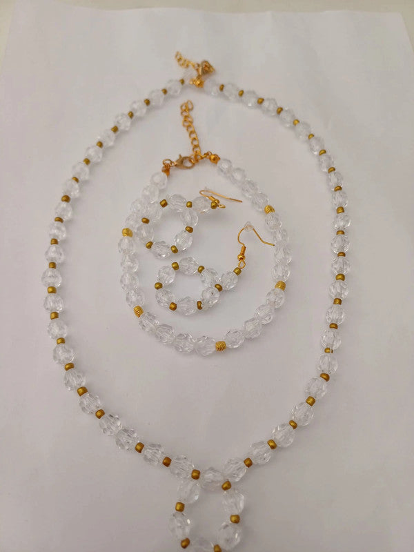 A jewelry set on a white background, featuring a clear bead necklace with gold accents, matching bracelet, and two earrings.