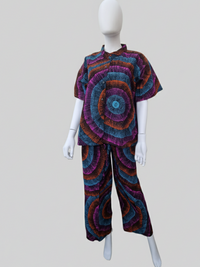 Mannequin wearing a colorful outfit with concentric circle patterns in blue, purple, and orange, featuring a short-sleeve top and matching pants.