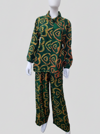 Mannequin wearing a green button-up shirt and pants with a yellow and red heart pattern on a plain background.