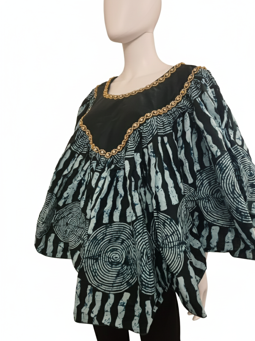 A mannequin wears the Black & Mint Green Ankara Batik Poncho Top, featuring Afro-inspired circular and vertical patterns. Gold trim lines the neckline, while wide sleeves and a voluminous shape create a chic look.