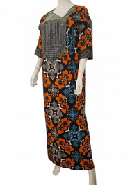 A mannequin showcases the African Print Maxi Dress – Vibrant Floral Pattern, featuring half sleeves, orange, blue, and black floral prints, and a geometric panel on the chest.