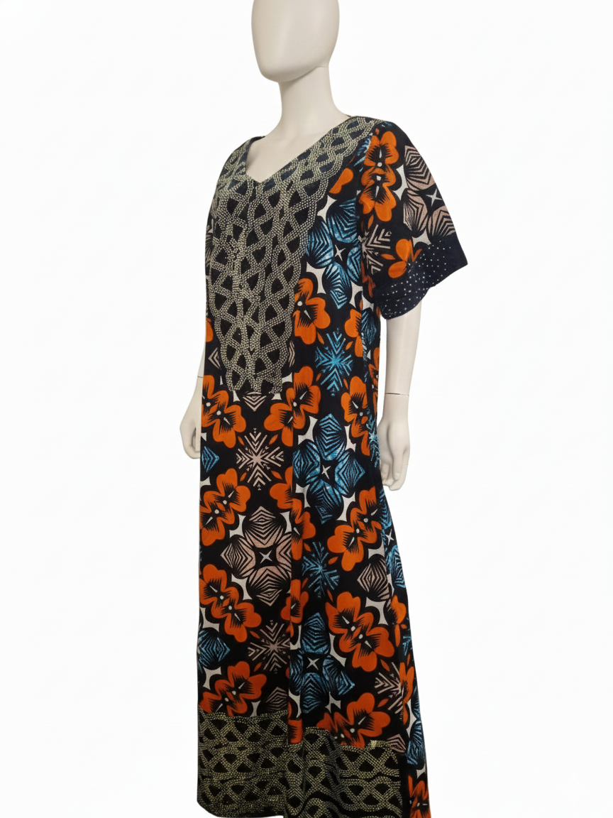 A mannequin displays the African Print Maxi Dress—an airy, short-sleeved dress with a V-neck and a vibrant orange, blue, black, and beige floral geometric pattern on white.