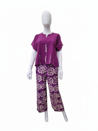 Mannequin wearing a purple short-sleeve top and patterned purple pants with white geometric designs, against a white background.