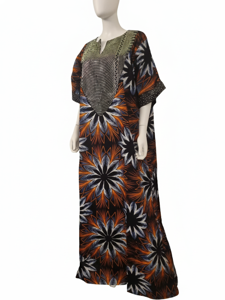 A mannequin showcases the Ankara Maxi Dress – Bold Sunburst Floral Print (Orange, Black & White), featuring short sleeves, a vibrant sunburst floral pattern, and a decorative neckline—ideal for cultural events.